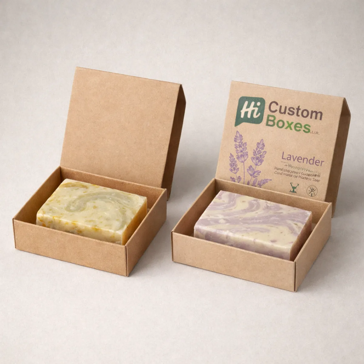 Two square kraft paper boxes with flip-top lids, each containing a marbled bar of lavender and citrus soap. class=
